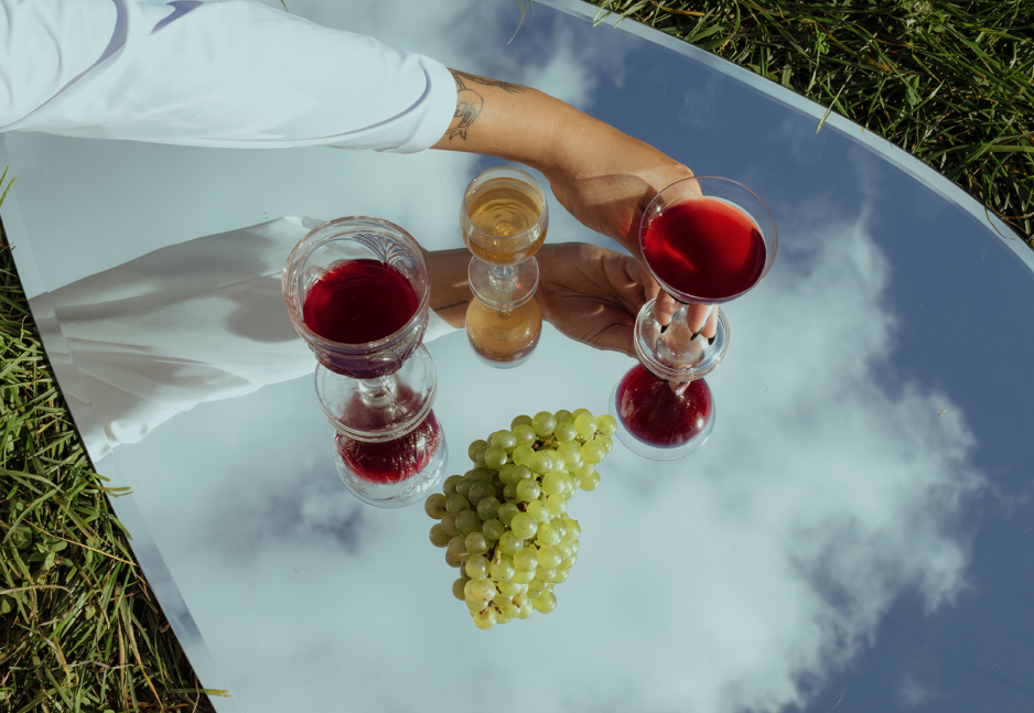 Hand grabbing wine glass on blanket next to grapes